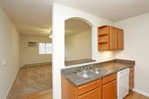 This single-floor unit offers a practical and straightforward layout, as revealed by the 3D floor plan, encompassing a living area, kitchen, bedroom, and bathroom. The living area is finished with neutral-toned wall-to-wall carpeting and features a ceiling fan with integrated lighting overhead. An arched pass-through opening connects the living space to the kitchen, adding a subtle architectural detail. A wall-mounted air conditioning unit and baseboard heating are also present, ensuring year-round climate control.

The kitchen is outfitted with warm-toned wood cabinetry, both upper and lower, providing ample storage. White appliances, including a refrigerator, electric range, and microwave, are included. Light hardwood flooring runs throughout the kitchen, offering a clean contrast to the carpeted living spaces.

The bedroom is a well-proportioned room with the same neutral carpet, a ceiling fan with lighting, a window that lets in natural light and outdoor views, and baseboard heating along the exterior wall.

The bathroom is clean and functional, featuring a full-sized soaking tub with an overhead shower, chrome fixtures, and a straightforward, easy-to-maintain design. Overall, the space maintains a bright, neutral palette throughout.