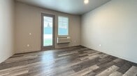 This 340 square foot studio apartment in Kalispell, Montana, offers a thoughtfully designed living space that maximizes functionality. The open-concept layout combines the kitchen, living room, and bedroom areas, creating a seamless flow throughout the unit. The space boasts modern finishes, including sleek laminate flooring that resembles weathered wood, adding warmth and character.

The kitchen is equipped with dark wood cabinetry, stainless steel appliances, and light-colored countertops, providing a contemporary contrast. A glass-door microwave and electric range offer convenient cooking options. The bathroom features a single vanity with a dark wood base and a light-colored countertop, maintaining the cohesive design aesthetic.

Large windows and a glass door allow ample natural light to flood the space, enhancing the sense of openness. A wall-mounted air conditioning unit provides climate control. The neutral color palette, primarily in shades of white and gray, creates a clean and calming atmosphere.

Storage solutions are integrated throughout, with closet spaces visible in the 3D render. The compact yet efficient design makes this studio an ideal option for those seeking a minimalist lifestyle or as an investment property in the heart of Kalispell.
