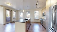 Located at 1910 S Josephine St in Denver, CO, this well-appointed two-bedroom, two-bathroom residence offers a thoughtfully designed single-level layout. The open-concept kitchen and living area serves as the heart of the home, showcasing a large central island with a dark countertop, undermount sink, and pendant lighting. Warm wood-tone cabinetry, a subway tile backsplash, stainless steel appliances, and track lighting complete the kitchen's modern aesthetic. Hardwood-style flooring flows throughout the main living areas, bathed in natural light from multiple double-hung windows with views of the surrounding neighborhood. A glass door leads to a private balcony, extending the living space outdoors. The hallway connects the two carpeted bedrooms, each offering a calm, neutral palette; the primary bedroom includes a ceiling fan and dual windows, while the en-suite bathroom features a double-sink vanity with dark countertops, wood-grain cabinetry, large-format tile flooring, and a glass-enclosed shower. The second bathroom mirrors the same refined finishes. A dedicated laundry area with a full-size washer and dryer adds everyday convenience. Five closets throughout provide generous storage, rounding out this functional and stylish Denver residence.