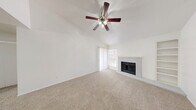 Located at 1930 W Rundberg Ln in Austin, TX, this one-bedroom, one-bathroom home offers a thoughtfully arranged single-level floor plan. The living room is a standout space, featuring vaulted ceilings, a ceiling fan, soft carpet flooring, a brick-surround fireplace, and a sliding glass door flanked by windows that invite natural light and outdoor views. Built-in shelving adds a functional architectural detail to the room.

The kitchen is positioned adjacent to the living area with a pass-through counter that enhances the open feel. It is equipped with gray cabinetry, a stainless steel sink, a dishwasher, an electric range, and a refrigerator, all set atop durable wood-look flooring that extends into the bathroom.

The bedroom offers a comfortable layout with plush carpet, a ceiling fan with light fixture, a closet, and a window overlooking the exterior. The full bathroom features a wide vanity with ample cabinet storage, a large mirror, and a tub-shower combination, all complemented by the warm wood-look flooring. The home's clean white walls and neutral finishes throughout create a bright, cohesive atmosphere well-suited for everyday living.