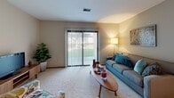 Located at 1359 Dewberry Pl NE in Grand Rapids, Michigan, this single-floor residence offers a well-organized layout designed for comfortable everyday living. The living room provides a welcoming gathering space with soft carpeting, neutral walls, and a sliding door that invites natural light. A hallway connects the main areas seamlessly, with warm wood-toned doors adding a classic touch throughout.

The kitchen is efficiently designed with warm oak cabinetry, ample counter space, and white appliances including a range and a full-size refrigerator. Tile flooring and under-cabinet lighting contribute to a practical and tidy cooking environment. Adjacent to the kitchen, the dining area accommodates a full-size dining table beneath a pendant light fixture, with carpeted floors and decorative wall art creating an inviting atmosphere for meals.

The primary bedroom benefits from multiple windows that allow generous natural light, complemented by neutral carpet and soft, neutral-toned walls. A second bedroom features similar finishes, with a desk space suited for work or study. A flexible bonus room with carpet can serve as a sitting area or den. The bathroom is fitted with a clean, white tub-shower combination with chrome fixtures. Throughout the home, consistent neutral tones and carpet flooring create a cohesive, comfortable living environment.