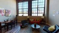 Located at 415 Valley St in Providence, Rhode Island, this two-floor loft-style residence showcases a compelling blend of industrial heritage and contemporary living. The main living area immediately captures attention with its soaring ceilings, expansive factory-style windows framed in black steel, and original exposed brick walls that flood the space with natural light and urban character. Wide-plank hardwood flooring runs throughout the main level, complementing the open, airy layout. An exposed ductwork detail adds to the industrial aesthetic overhead.

The kitchen is well-appointed with white shaker-style cabinetry, granite countertops, stainless steel appliances including a side-by-side refrigerator and range, and a dedicated sink area — offering both style and functionality. The space features multiple bedrooms across its two floors: one upper-level bedroom is distinguished by a striking wood-beamed ceiling and closet access, while a lower-level bedroom offers a more intimate, cozy atmosphere with warm neutral tones.

Two full bathrooms mirror each other in design, each featuring wood-look tile flooring, granite-topped vanities, and tub-shower combinations. A staircase connects both floors, reinforcing the loft's vertical scale. Overall, this residence delivers an authentic live-work aesthetic rooted in Providence's architectural history.