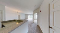 Located at 197 Attenborough Dr in Nottingham, Maryland, this single-floor residence offers a well-designed, open layout that maximizes livability and comfort. The main living and dining area is generously proportioned, featuring neutral-toned carpet throughout and crisp white walls that create a bright, airy atmosphere. A sliding glass door floods the living room with natural light and provides direct access to an outdoor balcony, offering pleasant views of the surrounding community.

The kitchen is thoughtfully appointed with rich, dark espresso-toned cabinetry contrasted by light granite-style countertops. Stainless steel appliances — including a gas range, built-in microwave, refrigerator, and dishwasher — are complemented by hardwood-style flooring. A peninsula with pendant lighting separates the kitchen from the living space, creating a natural flow ideal for entertaining.

The bedroom is a calm, carpeted retreat bathed in natural light through double windows with blinds. The bathroom features a white vanity with a single-basin sink, a large mirror, wood-style flooring, and a separate walk-in shower with chrome fixtures, offering a clean and functional design. Throughout the residence, neutral tones, consistent finishes, and practical layouts come together to create a comfortable and cohesive living environment.