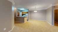 This single-floor residence at 1875–1879 Woodruff Rd in Greenville, South Carolina offers a well-organized and functional layout designed for comfortable living. The kitchen is a central highlight, featuring warm wood cabinetry, light countertops with a peninsula that opens to the dining and living areas, wood-look flooring, a double-basin sink, and white appliances. A pendant chandelier adds a decorative touch above the peninsula, while crown molding provides a refined detail in the adjoining living space. The generously sized living room is finished with plush carpeting, a ceiling fan, and a window that admits natural light, creating a bright and airy atmosphere. Multiple bedrooms are carpeted and neutrally painted in warm taupe tones, each featuring windows with blinds. Several bedrooms include walk-in or reach-in closets with built-in shelving and hanging rods for ample storage. The bathrooms are practical and well-appointed: one features a tub-shower combination with tile surround and wood-look flooring, while the primary bathroom includes a vanity with an extended countertop, a large mirror with overhead lighting, and a separate tub-shower. Textured ceilings are present throughout, and the consistent neutral color palette gives the entire space a cohesive, move-in-ready feel.