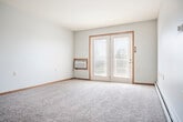 Located at 3125 Pennsylvania Ave in Dubuque, Iowa, this single-floor, 2-bedroom, 2-bathroom unit offers a functional and comfortable layout. The living area features light hardwood-style flooring, a ceiling fan, and an open pass-through window connecting to the kitchen, creating a bright and connected feel. Carpeted bedrooms provide a cozy atmosphere; the primary bedroom is generously sized with multiple windows that invite natural light and a ceiling fan overhead, while the second bedroom includes a sliding wood-panel closet and baseboard heating. The kitchen is well-equipped with rich dark cabinetry, light marble-style countertops, stainless steel appliances, and a breakfast bar peninsula — all set on light vinyl plank flooring. Two bathrooms serve the unit: one features a full tub/shower combo with a dark wood vanity, while the second includes a walk-in glass shower and a lighter vanity. A dedicated in-unit laundry room adds everyday convenience. The unit also includes a private outdoor deck with white railing, offering pleasant views of the landscaped surroundings and neighborhood. A hallway and closet round out the practical layout of this well-maintained space.