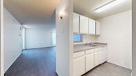 Located at 693 Urban Ct in Lakewood, Colorado, this single-floor, one-bedroom, one-bathroom unit offers a functional and comfortable layout throughout. The combined kitchen and living area forms the heart of the home, featuring durable hardwood-style flooring and a textured ceiling. Large sliding glass doors in the living room provide direct access to a private balcony, filling the space with natural light and offering outdoor views. The kitchen is efficiently designed with white upper and lower cabinetry, laminate countertops, a stainless steel sink, a dishwasher, and a full-size refrigerator — providing ample storage and workspace. A wall sconce adds a touch of warmth at the kitchen's entrance. The spacious primary bedroom is generously sized, highlighted by a large window with balcony views that bring in abundant natural light and a connection to the outdoors. The bathroom includes a full tiled tub/shower combination with a grab bar, paired with wood-style flooring. A dedicated closet and hallway complete the layout, offering practical storage solutions. White walls and neutral tones throughout create a clean, bright atmosphere well-suited for a variety of living arrangements.