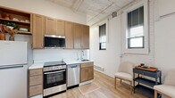 Located at 1707 Main St in La Crosse, Wisconsin, this 2-bedroom, 1-bathroom unit offers a practical and comfortable single-floor layout. The open-plan living and kitchen area anchors the space, featuring light hardwood-style flooring, white-painted exposed ceilings that lend an industrial character, and recessed lighting. The kitchen is outfitted with warm wood cabinetry, stainless steel appliances including a range, dishwasher, and refrigerator, along with a clean tile backsplash and sink. The living area provides ample room for seating and benefits from natural light through windows fitted with blinds. A hallway connects the main living space to the private rooms. The primary bedroom is carpeted and includes a closet, offering a quiet retreat. The second bedroom is also carpeted, features baseboard heating, and provides a flexible, open space. A cozy nook with a large window adds a bright, relaxing corner to the unit. The full bathroom includes a combination tub and shower, vanity with storage, and hardwood-style flooring. Neutral tones and clean finishes throughout create a cohesive, move-in-ready atmosphere suited for comfortable everyday living.