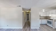 This single-floor residence at 42200 Moraga Rd in Temecula, California offers a clean, functional layout designed for comfortable everyday living. Consistent light wood-style flooring runs throughout the unit, complemented by neutral warm-beige walls and textured ceilings that create a cohesive, move-in-ready aesthetic.

The kitchen is efficiently appointed with white cabinetry, granite-look countertops, a double-basin stainless steel sink, and white appliances including a refrigerator, dishwasher, and range. Ample upper cabinet storage makes the space highly practical.

A central hallway connects the living areas to the bedrooms, each of which features generous proportions, wood-style flooring, and windows that bring in natural light and views of surrounding greenery. The living area is highlighted by a ceiling fan with light fixture and a large window dressed with vertical blinds, allowing for flexible light control.

Two full bathrooms serve the unit, each featuring a tub-shower combination, granite-look vanity countertops, large mirrors, and clean white fixtures. The consistent finishes across both bathrooms lend a uniform, well-maintained feel throughout. Overall, the space presents a tidy, straightforward layout well-suited to those seeking a comfortable home in the Temecula area.