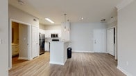 Located in New Orleans, LA, this single-floor residence offers a well-designed open-concept layout that seamlessly connects the kitchen, dining, and living areas. Light wood-tone flooring runs throughout the main living spaces, creating a cohesive and clean aesthetic. The kitchen is outfitted with white shaker-style cabinetry, granite-look countertops, a full suite of stainless steel appliances including a refrigerator, electric range, and over-the-range microwave, and a peninsula with pendant lighting overhead that doubles as a breakfast bar. The spacious living area benefits from crown molding details and natural light from a window with blinds.

The two bedrooms feature plush carpeting, ceiling fans, and ample closet space, including a walk-in closet in the primary bedroom. The primary bathroom includes a white vanity with extended cabinet storage, wood-look flooring, and a glass-enclosed stand-up shower. The secondary bathroom mirrors the clean aesthetic with a white vanity and a full tub-shower combination with tile surround. Neutral wall tones throughout contribute to the space's bright, modern ambiance.
