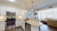 Located at 29 Dexter Rd in Foxboro, MA, this single-floor residence offers a thoughtfully designed open-concept layout that connects the kitchen, dining, and living areas seamlessly. The kitchen is a standout feature, showcasing white shaker cabinetry, granite countertops, and a full suite of stainless steel appliances including a refrigerator, range, microwave, and dishwasher. A curved peninsula with pendant lighting overhead provides bar seating for three, making it an ideal space for casual dining or entertaining. Wood-style plank flooring flows throughout the common areas, adding warmth and continuity.

The living room benefits from large windows and a glass door that invite abundant natural light and offer outdoor views. Crown molding adds an architectural detail that elevates the overall aesthetic. The bedrooms are comfortably sized, each receiving natural light through well-positioned windows. The primary bedroom connects to a bright full bathroom featuring a double-sink vanity with granite countertops, white cabinetry, and tile flooring. A second bathroom offers similar finishes with a shower-tub combination. Additional storage is accessible via bifold closet doors. The overall ambiance is clean, modern, and welcoming.