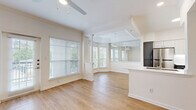 Located at 2424 E TC Jester Blvd in Houston, TX, this well-appointed one-bedroom, two-bathroom residence offers a thoughtfully designed single-floor layout. The open-concept living and dining area is a standout feature, boasting light hardwood-style flooring, a ceiling fan, and a charming bay window nook framed by decorative columns that floods the space with natural light. A glass-panel wall separates the dining area from the kitchen, adding an airy, modern touch. A private exterior door leads to an outdoor area, further enhancing the connection to the outdoors. The kitchen is fully equipped with stainless steel appliances — including a refrigerator, range, and microwave — complemented by two-tone cabinetry featuring white upper cabinets and slate-gray lower cabinets, white quartz countertops, and an undermount sink set into a peninsula. The spacious bedroom features plush carpeting, a ceiling fan, a window with natural light, and access to a dedicated closet with built-in shelving. Both bathrooms are finished with gray vanity cabinetry, white quartz countertops, large mirrors, and light wood-style flooring, with one bath offering a full tub-shower combination. Clean white walls and consistent finishes create a bright, cohesive ambiance throughout.