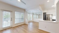 Located at 2424 E TC Jester Blvd in Houston, TX, this well-appointed one-bedroom, two-bathroom residence offers a thoughtfully designed single-floor layout. The open-concept living and dining area is a standout feature, boasting light hardwood-style flooring, a ceiling fan, and a charming bay window nook framed by decorative columns that floods the space with natural light. A glass-panel wall separates the dining area from the kitchen, adding an airy, modern touch. A private exterior door leads to an outdoor area, further enhancing the connection to the outdoors. The kitchen is fully equipped with stainless steel appliances — including a refrigerator, range, and microwave — complemented by two-tone cabinetry featuring white upper cabinets and slate-gray lower cabinets, white quartz countertops, and an undermount sink set into a peninsula. The spacious bedroom features plush carpeting, a ceiling fan, a window with natural light, and access to a dedicated closet with built-in shelving. Both bathrooms are finished with gray vanity cabinetry, white quartz countertops, large mirrors, and light wood-style flooring, with one bath offering a full tub-shower combination. Clean white walls and consistent finishes create a bright, cohesive ambiance throughout.