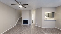 Located at 2512 Northwest Dr, this two-bedroom, one-bathroom two-story home offers a thoughtfully arranged layout spread evenly across two floors. The main level features an open-concept living room and kitchen area with light gray wood-look flooring throughout. The living room is highlighted by a brick-surround fireplace, a ceiling fan with lighting, and a textured ceiling. French doors with slatted blinds allow natural light to fill the space and provide outdoor access. The kitchen is well-appointed with gray cabinetry, a white quartz countertop with a breakfast bar overhang, a subway tile backsplash, and stainless steel appliances including a refrigerator and range. A carpeted staircase leads to the upper level, where both bedrooms are located. The primary bedroom is generously sized, featuring wood-look flooring, a ceiling fan, and a window for natural light. The second bedroom is carpeted and includes a window with blinds. The shared bathroom features wood-look flooring, a vanity with a white countertop, and gray cabinetry, tucked beneath a sloped ceiling detail. The primary bedroom offers convenient access to the bathroom and an adjacent closet with built-in shelving, adding practical storage to the upper floor.