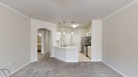 Located at 1000 S Denver Ave in Tulsa, Oklahoma, this thoughtfully designed one-bedroom, one-bathroom residence offers a comfortable and functional layout across a single floor. The open-concept living and kitchen area serves as the heart of the home, where a curved peninsula with a sleek white countertop and an undermount sink anchors the space. Pendant lighting hangs above the peninsula, complementing the white cabinetry with glass-front accents, a subway tile backsplash, and a full suite of stainless steel appliances including a refrigerator, range, microwave, and dishwasher. Light tile flooring runs through the kitchen, while plush carpet extends into the living area. An elegant arched doorway connects the living space to the hallway, adding a classic architectural touch. Crown molding and a ceiling fan elevate the living room, which is highlighted by a white-mantled fireplace and a trio of windows that invite natural light. The spacious primary bedroom features carpeted floors, a ceiling fan, a window with natural light, and a walk-in closet. The bathroom is finished with tile flooring, a wide vanity with a large framed mirror, and a full tub-shower combination.