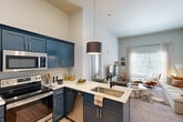 Located at 1016 S Broadway in Lexington, KY, this efficiently designed one-bedroom, one-bathroom residence makes excellent use of its thoughtfully laid-out single floor. The open-concept kitchen flows seamlessly into the living area, anchored by striking navy blue shaker-style cabinetry paired with crisp white quartz countertops and a full suite of stainless steel appliances, including a refrigerator, range, microwave, and dishwasher. A peninsula with an undermount sink and pendant lighting above adds both function and style to the kitchen. The living room benefits from soaring ceilings and a large window that fills the space with natural light, creating an airy, open atmosphere. The bedroom features the same impressive ceiling height, accented with a teal-painted upper wall, plush carpeting, and a window for additional natural light. A dedicated closet is directly accessible from the bedroom, offering practical storage. The full bathroom includes a tub-shower combination, wood-look flooring, and clean, modern finishes throughout. Light, neutral tones across all rooms contribute to a cohesive and welcoming ambiance throughout the entire residence.