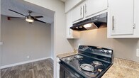 This single-floor residence offers a thoughtfully organized layout with a clean, neutral aesthetic throughout. The living areas feature durable wood-look plank flooring in a warm, multi-toned finish, complemented by soft gray walls and crisp white baseboards. A ceiling fan is present in the main living space, and a sliding glass door floods the room with natural light while providing direct access to the outdoors. The open flow between the living and dining areas creates a comfortable, functional space for everyday living.

The galley-style kitchen is efficiently designed, featuring white cabinetry with brushed nickel hardware, granite-style countertops, a stainless steel sink, and black appliances including an electric range and refrigerator. An overhead range hood and ample upper and lower cabinet storage add to the kitchen's practicality.

The bedrooms are finished with plush carpeting and feature windows that bring in natural light. The neutral wall tones carry throughout, creating a cohesive and calm ambiance. The bathroom includes a wide vanity with white cabinetry, a solid-surface countertop, a large mirror, and hardwood-style flooring. Textured ceilings are present throughout the space, adding a classic residential character to every room.
