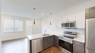 Located at 1701 Federal St in Philadelphia's vibrant Graduate Hospital neighborhood, this thoughtfully designed one-bedroom, one-bathroom unit delivers modern living with quality finishes throughout. The open-concept kitchen serves as the centerpiece of the space, featuring two-tone cabinetry with dark lower cabinets and crisp white uppers, a herringbone tile backsplash, white quartz countertops, and a full suite of stainless steel appliances including a refrigerator, electric range, microwave, and dishwasher. Sleek pendant lighting adds a contemporary touch above the kitchen peninsula, which provides additional workspace and casual dining space. Warm hardwood flooring flows consistently throughout the unit, complementing the clean white walls and modern blue-gray interior doors. The bedroom is a quiet, well-proportioned retreat filled with natural light from a window fitted with white blinds. The bathroom offers a calm, spa-like atmosphere with large-format tile flooring, marble-style tile surrounding the soaking tub and shower, a modern vanity with wood cabinetry, and a frosted glass door for privacy. A hallway connects the rooms efficiently, completing this well-organized and move-in-ready unit.