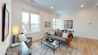 This single-floor residence is thoughtfully designed with a cohesive, light-filled aesthetic carried throughout each room. Light hardwood flooring runs continuously across the entire space, complementing the crisp white walls and creating a warm, unified feel.

The kitchen is well-appointed with white shaker-style cabinetry extending to the ceiling, offering generous storage. Granite countertops provide ample workspace, and stainless steel appliances — including a range, over-the-range microwave, refrigerator, and dishwasher — complete the functional layout. A stainless steel sink sits beneath upper cabinets, rounding out the clean, classic look.

The living and dining area benefits from multiple large windows that invite abundant natural light and outdoor views. Recessed lighting adds to the bright ambiance, while the open layout allows the kitchen, dining, and living zones to flow naturally together.

The two bedrooms are calm and understated, each featuring large windows with outdoor views, ample closet space, and the same warm hardwood flooring. The hallway connecting the rooms is clean and well-proportioned.

The bathroom features granite countertops consistent with the kitchen, a walk-in shower, and hardwood-style flooring, maintaining the cohesive design found throughout the space.