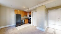 Located at 313 Market St in downtown Harrisburg, Pennsylvania, this efficiently designed unit offers a practical and functional layout across a single floor. The living area features neutral-toned walls, wall-to-wall carpeting, and two large multi-pane windows that flood the space with natural light while framing views of the surrounding urban streetscape. Clean white baseboards and recessed ceiling details add a crisp, polished finish throughout.

The kitchen is thoughtfully appointed with warm wood cabinetry extending to the ceiling, providing ample storage space. Dark granite-style countertops and a full suite of black appliances — including a refrigerator, electric range, over-the-range microwave, and dishwasher — give the kitchen a cohesive, modern look. A closet adjacent to the kitchen adds additional storage convenience.

The bathroom is clean and straightforward, featuring a tub-shower combination with white surround, a wood-toned vanity with granite-style countertop, brushed nickel fixtures, and tile flooring. The overall aesthetic throughout the unit is consistent — neutral beige tones, practical finishes, and an open feel that maximizes the available footprint. This unit is ideally situated in the heart of downtown Harrisburg, offering easy access to the city's business and cultural amenities.
