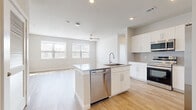 This well-designed single-floor residence offers a clean, modern aesthetic with an open-concept layout that seamlessly connects the kitchen, dining, and living areas. Light wood-tone flooring runs throughout, complementing the bright white walls and creating a cohesive, airy atmosphere.

The kitchen serves as the centerpiece of the main living area, anchored by a central island with granite countertops and a stainless steel sink and dishwasher. White shaker-style cabinetry extends to the upper walls, accented by a neutral subway tile backsplash. A full suite of stainless steel appliances — including a refrigerator with ice maker, electric range, and over-the-range microwave — completes the space.

The living area is generously sized and bathed in natural light from multiple windows with horizontal blinds. A ceiling fan overhead adds comfort and functionality.

The bedroom is a comfortable, well-proportioned room featuring natural light from a window, a ceiling fan, and access to a dedicated closet. The neutral color palette and light flooring maintain the home's consistent, modern feel.

The bathroom is thoughtfully finished with a granite-topped vanity, white cabinetry, a large mirror, and a tub-shower combo with floor-to-ceiling marble-style tile surround, adding a refined touch to the space.