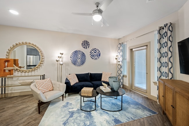 Living room with an attached balcony at The Alexa Luxury Apartments in Corpus Christi, TX. - The Alexa Luxury Apartments I & II