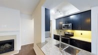 Located at 4405 Waterford Valley Dr in Durham, North Carolina, this single-floor residence offers a thoughtfully designed living space with contemporary finishes throughout. The kitchen is a standout feature, showcasing striking dark navy cabinetry that contrasts beautifully with light granite countertops. Stainless steel appliances—including a range, built-in microwave, and refrigerator—complete the modern look. A yellow glass tile backsplash adds a pop of color and visual interest, while a deep undermount sink with a sleek pull-down faucet makes for a highly functional workspace. The kitchen opens to the adjoining living area through a structural column detail, creating a connected yet defined layout. Track lighting illuminates the kitchen efficiently, while the neutral-toned walls and flooring throughout the space provide a clean, versatile backdrop. The open sightlines between rooms contribute to an airy, cohesive feel across the single level. Overall, the space combines practical design with stylish details, making it a comfortable and attractive home in the Durham area.