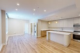 Located at 625 Jackson Ave in New Orleans, this thoughtfully designed one-bedroom, one-bathroom residence offers a streamlined, modern living experience across a single floor. Light-toned hardwood flooring flows continuously throughout, unifying the open-concept living, dining, and kitchen area into one cohesive and welcoming space. Recessed lighting complements large, black-framed windows that invite natural light and offer views of the surrounding cityscape.

The chef-inspired kitchen is a standout feature, showcasing an L-shaped layout with a generous central island topped in white quartz. Two-tone cabinetry pairs flat-front white upper cabinets with warm wood lower cabinets, while stainless steel appliances — including a refrigerator, range, and microwave — complete the space. Distinctive yellow pendant lights add a touch of personality overhead.

In-unit stacked laundry is conveniently tucked just off the main living area. The bedroom offers a comfortable footprint with a ceiling fan, a large window with urban views, and direct access to two closets and the full bathroom. The bathroom features light tile flooring, a glass-enclosed shower, and a sleek vanity with quartz countertops, maintaining the home's clean, contemporary aesthetic throughout.