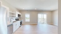 Located on Garland Ave in Norwalk, Iowa, this one-bedroom, one-bathroom unit offers a well-designed, efficiently arranged single-floor layout. The open-concept kitchen and living area serves as the heart of the space, featuring light hardwood-style flooring that flows throughout the main areas. The kitchen is outfitted with crisp white shaker cabinetry, open shelving, light quartz countertops, a stainless steel undermount sink, and a full suite of stainless steel appliances including a side-by-side refrigerator, dishwasher, and range. Recessed lighting adds a clean, modern touch overhead. The living area is bright and open, with neutral-toned walls and access to a private balcony through sliding glass doors that frame an open outdoor view — filling the space with natural light. The bedroom offers plush carpeting, a ceiling fan, and a sliding-door closet providing ample storage. The full bathroom is finished with white cabinetry, a single vanity with a white countertop, brushed nickel hardware, and a tub/shower combination with light hardwood-style flooring completing the clean, cohesive aesthetic. The overall ambiance is modern, clean, and move-in ready.
