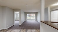 This 2-bedroom, 2-bathroom residence offers a practical and comfortable single-floor layout designed to maximize functionality. The open-concept kitchen and living area serves as the heart of the home, where the kitchen features light wood cabinetry, dark laminate countertops with a peninsula breakfast bar, white appliances including a refrigerator and range, and tile-style flooring. Track lighting illuminates the kitchen, while the adjoining living room transitions to plush carpeting and is filled with natural light from a large sliding glass door that opens to a balcony with outdoor views. The neutral grey and white color palette throughout creates a clean, cohesive atmosphere. Both bedrooms are carpeted and offer generous proportions, with the primary bedroom featuring a closet with bi-fold doors and track lighting. A dedicated closet provides additional storage. The two bathrooms include a full tub and shower surround. A standout feature is the in-unit laundry room equipped with a stacked washer and dryer, adding everyday convenience. Baseboard heating is present throughout the living areas, ensuring year-round comfort. Overall, the space presents a bright, functional layout suited for comfortable residential living.