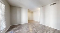 Located at 2249 Bridgeview Dr in Arlington, TX, this single-story 2-bedroom, 1-bathroom home offers a thoughtfully arranged layout with a clean, neutral aesthetic throughout. Wood-look plank flooring runs continuously across the living areas and bedrooms, lending a cohesive, modern feel to the entire space.

The living room is bright and open, featuring a textured ceiling and a door with an adjacent window that invites natural light in. It flows naturally toward the kitchen, which is outfitted with gray cabinetry, black hardware accents, white countertops, and a classic subway tile backsplash — providing both style and functionality. A window above the counter area keeps the kitchen airy and well-lit.

The primary bedroom is generously proportioned and includes a ceiling fan with light fixture, a window with blinds, and access to a dedicated closet with built-in shelving. The secondary bedroom is comparably comfortable, also featuring a window with natural light and its own closet. Both rooms maintain the same neutral color palette and durable flooring found throughout the home.

The bathroom is neatly appointed with a light gray vanity, white countertop, black hardware, and a combined tub-shower unit, reflecting a consistent modern design sensibility. A hallway connects all rooms efficiently, completing the practical and well-organized floor plan.