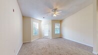 Located at 8465 Patriot Blvd in North Charleston, SC, this single-floor, one-bedroom, one-bathroom residence offers a well-organized layout across a comfortable footprint. The living room is a welcoming space featuring warm neutral-toned walls, plush carpet flooring, a textured ceiling, and a ceiling fan with integrated lighting. Multiple windows, including a glass-paned exterior door, allow natural light to fill the room while providing outdoor views of the surrounding greenery. The kitchen is efficiently designed with white cabinetry, light countertops, a double stainless steel sink, and a white range, delivering a clean and functional cooking space. The bedroom is a comfortably sized retreat with carpeted floors, a ceiling fan, a window for natural light, and direct access to a dedicated walk-in closet offering ample storage. A second closet provides additional organization options. The full bathroom features a vanity with sink, a toilet, and a full-size soaking tub with shower. The dedicated laundry area includes washer and dryer hookups with wire shelving above for added utility. Throughout the unit, consistent warm beige tones, white trim, and textured ceilings create a cohesive, neutral aesthetic.