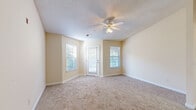 Located at 8465 Patriot Blvd in North Charleston, SC, this single-floor, one-bedroom, one-bathroom residence offers a well-organized layout across a comfortable footprint. The living room is a welcoming space featuring warm neutral-toned walls, plush carpet flooring, a textured ceiling, and a ceiling fan with integrated lighting. Multiple windows, including a glass-paned exterior door, allow natural light to fill the room while providing outdoor views of the surrounding greenery. The kitchen is efficiently designed with white cabinetry, light countertops, a double stainless steel sink, and a white range, delivering a clean and functional cooking space. The bedroom is a comfortably sized retreat with carpeted floors, a ceiling fan, a window for natural light, and direct access to a dedicated walk-in closet offering ample storage. A second closet provides additional organization options. The full bathroom features a vanity with sink, a toilet, and a full-size soaking tub with shower. The dedicated laundry area includes washer and dryer hookups with wire shelving above for added utility. Throughout the unit, consistent warm beige tones, white trim, and textured ceilings create a cohesive, neutral aesthetic.