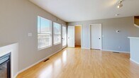 This three-story townhouse in Kansas City, MO is thoughtfully laid out across three distinct levels. The ground floor houses an attached garage equipped with an automatic opener, offering convenient enclosed parking and additional storage space, along with a utility room.

The main living level features an open-concept kitchen and living room area. The living room is bright and airy, with large windows that invite natural light and a corner gas fireplace as a focal point, set atop light hardwood-style flooring. The kitchen is well-appointed with warm honey-toned wood cabinetry, stainless steel appliances including a refrigerator, range, and microwave, a dishwasher, ample counter space, and a chandelier overhead. A staircase with a wood railing connects this level to the upper floor, and a half or full bathroom is also accessible on this level.

The upper floor contains both bedrooms and additional bathrooms. The primary bedroom features plush carpeting, a ceiling fan, a walk-in closet, and an en-suite bathroom. The second bedroom also offers carpeted flooring, a ceiling fan, and a distinctive arched window that frames outdoor views. The bathrooms throughout feature tile flooring, wood vanity cabinetry, and clean, neutral finishes.