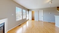 This three-story townhouse in Kansas City, MO is thoughtfully laid out across three distinct levels. The ground floor houses an attached garage equipped with an automatic opener, offering convenient enclosed parking and additional storage space, along with a utility room.

The main living level features an open-concept kitchen and living room area. The living room is bright and airy, with large windows that invite natural light and a corner gas fireplace as a focal point, set atop light hardwood-style flooring. The kitchen is well-appointed with warm honey-toned wood cabinetry, stainless steel appliances including a refrigerator, range, and microwave, a dishwasher, ample counter space, and a chandelier overhead. A staircase with a wood railing connects this level to the upper floor, and a half or full bathroom is also accessible on this level.

The upper floor contains both bedrooms and additional bathrooms. The primary bedroom features plush carpeting, a ceiling fan, a walk-in closet, and an en-suite bathroom. The second bedroom also offers carpeted flooring, a ceiling fan, and a distinctive arched window that frames outdoor views. The bathrooms throughout feature tile flooring, wood vanity cabinetry, and clean, neutral finishes.