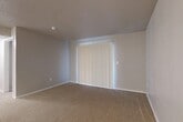This single-floor, 2-bedroom, 2-bathroom residence offers a practical and comfortable layout designed to maximize its footprint. The open living and dining area serves as the heart of the home, featuring warm beige carpeting, a ceiling fan, and direct access to the kitchen via a peninsula counter with a dark laminate surface. The kitchen is equipped with white cabinetry and appliances, providing ample storage and functionality. Both bedrooms are carpeted and finished with neutral tones. The primary bedroom is generously sized and features vertical blinds over a sliding door that allows natural light to filter in. The second bedroom benefits from a large window overlooking greenery, bringing in natural light and outdoor views. Both bathrooms are well-appointed; one features a tiled shower-tub combination, wood-look vinyl flooring, white cabinetry with wooden accents, and overhead storage. Textured ceilings are consistent throughout the space, adding a classic residential character. A dedicated closet and in-unit laundry area add everyday convenience. The overall ambiance is clean, neutral, and move-in ready, offering a solid foundation for personalization.