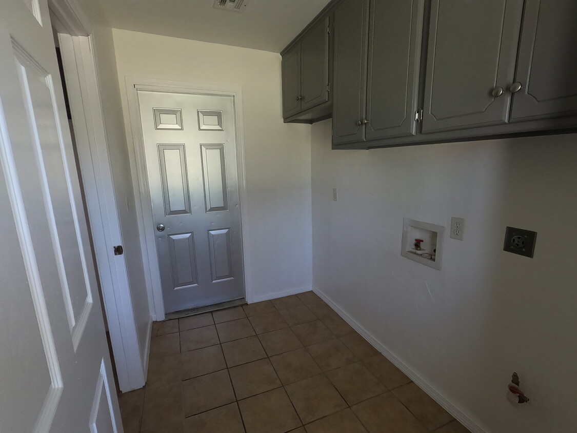 View of utility room with door to garage; there is a space for an additional fridge or upright freezer - lots of cabinet space - 415 W Guthrie St