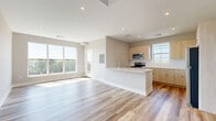 Located at 219 Ash Creek Boulevard in Fairfield, Connecticut, this thoughtfully designed 2-bedroom, 2-bathroom residence offers a clean, modern aesthetic throughout. Light-toned hardwood flooring flows seamlessly across the entire living area, creating a bright and cohesive atmosphere. The open-concept kitchen and living room serve as the heart of the unit, where large windows flood the space with natural light and frame pleasant outdoor views. The kitchen is well-appointed with light natural wood cabinetry, crisp white countertops, a large peninsula island, and stainless steel appliances including a refrigerator, range, and built-in microwave. The spacious primary bedroom features generous proportions and access to closet space, while the second bedroom benefits from a large window with outdoor views. Both bathrooms are finished with neutral tile flooring; the primary bath includes a glass-enclosed walk-in shower with elegant marble-style tile surround. Additional conveniences include a dedicated laundry area, four closets for ample storage, and a private balcony perfect for enjoying the surrounding greenery. Recessed lighting throughout enhances the unit's clean, contemporary feel.