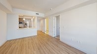 This single-floor residence showcases a thoughtfully designed layout with modern finishes and a clean, contemporary aesthetic. The open-concept living area features light wood-tone flooring, recessed lighting, and a large window that allows natural light to fill the space, creating a bright and airy atmosphere.

The kitchen is equipped with a stainless steel gas range topped by a matching range hood, complemented by granite-look countertops and warm wood-grain cabinetry with sleek hardware. A kitchen island with pendant lighting and stainless steel appliances, including a refrigerator and microwave, adds both functionality and visual appeal.

The bedroom offers plush carpeting, crisp white walls, and a window with horizontal blinds that provides views of the surrounding exterior. The room's neutral tones lend a calm, versatile atmosphere suitable for a variety of furnishing styles.

The bathrooms maintain the unit's modern character. One features a tub-shower combination with white tile surround, while another includes a wood-grain vanity with a white countertop, chrome hardware, and a large mirror. Both spaces are finished with clean, light-toned flooring and minimal, functional detailing throughout.