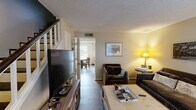 Located at 250 Elm St in Clemson, SC, this two-story, two-bedroom, two-bathroom home offers a practical and well-organized layout spread across two floors. The main level houses the living room, kitchen, and dining area. The living room features warm-toned walls, wood-style flooring, a textured ceiling, and natural light from windows, creating a comfortable gathering space. The kitchen is well-equipped with warm oak cabinetry, ample upper and lower storage, a stainless steel range, dishwasher, refrigerator, and a double sink beneath a window. An adjacent dining area provides space for a table and chairs. A hallway connects the main living areas, and a staircase leads to the upper floor. The upper level contains both bedrooms, two full bathrooms, and a laundry area. The primary bedroom offers a walk-in closet and a window with natural light, complemented by wood-style flooring. The second bedroom also features a closet and similar flooring. Both bathrooms include wood-toned vanities with white countertops and tile flooring. One bathroom features a shower-tub combination. The home's consistent wood-style flooring throughout both levels and neutral wall tones contribute to a cohesive, functional interior.