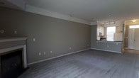 Located at 1669 College Park Dr in Columbus, Ohio, this two-floor property offers a well-designed layout suited for comfortable everyday living. The main living area is generously proportioned, featuring plush gray carpeting and neutral taupe-toned walls that create a calm, understated atmosphere. Crown molding lines the upper edges of the room, adding a subtle architectural touch that elevates the overall finish of the space. The open layout allows for flexible furniture arrangements and flows seamlessly into the kitchen area. The kitchen is visible from the living space and features white cabinetry, dark countertops, and track lighting overhead, providing both functional workspace and visual contrast against the lighter upper cabinets. A window in the kitchen area allows natural light to filter into the connected spaces, brightening the interior. The consistent neutral color palette throughout ties the main floor together cohesively. With two floors, the property offers separation between living and private areas, making it a practical and well-structured home. The clean, move-in-ready condition of the space reflects thoughtful maintenance and a straightforward, timeless interior design approach throughout.