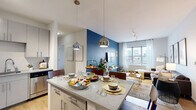 Located at 29 E Green St in Champaign, IL, this five-bedroom, four-bathroom unit offers a well-designed single-floor layout ideal for shared living. The open-concept kitchen and living area serves as the heart of the space, featuring sleek gray cabinetry, stainless steel appliances including a refrigerator, range, microwave, and dishwasher, and a granite-topped island with pendant lighting that doubles as a dining and gathering area. Light hardwood-style flooring runs throughout the main living areas, complementing the bright, airy atmosphere. The living room is anchored by large windows that invite abundant natural light and offer open city views, creating a comfortable and inviting retreat. A bold accent wall adds a contemporary design touch to the shared living space. Each bedroom is thoughtfully laid out with built-in closets featuring wire shelving and rack systems, and carpeted flooring for added comfort. The bathrooms are finished with gray vanities, granite countertops, wood-look tile flooring, and glass-enclosed showers, reflecting a clean and modern aesthetic throughout. The unit's efficient layout maximizes every square foot, making it a functional and stylish option in the heart of Champaign near the University of Illinois campus.