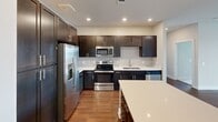 Located at 700 West Cavalcade Street in Houston's 77009 neighborhood, this well-appointed 2-bedroom, 2-bathroom residence offers a thoughtfully designed single-level layout. Rich hardwood-style flooring runs throughout the main living areas, anchoring a clean, neutral color palette. The open kitchen is a standout feature, showcasing dark espresso cabinetry, light quartz countertops, a center island, and a full suite of stainless steel appliances including a refrigerator with ice maker, range, microwave, and dishwasher — all illuminated by recessed lighting. The living room flows seamlessly from the kitchen and opens through sliding glass doors to a private balcony, offering views of a landscaped courtyard. A ceiling fan adds comfort to the airy living space. Both bedrooms are carpeted and feature ceiling fans and windows with exterior views, providing natural light throughout the day. The primary bedroom connects to an en-suite bathroom with dual-sink vanity, a glass-enclosed shower, and a walk-in closet with built-in shelving. The second bathroom is finished with matching dark cabinetry and a tiled shower surround. A dedicated closet provides additional storage, completing this well-rounded residence.