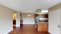 Located at 1617 Live Oak in Vista, this upstairs unit offers a well-designed single-floor layout that balances everyday functionality with comfortable living. The open-concept main living area is finished with rich hardwood-style flooring that extends throughout, creating a warm and cohesive feel. A sliding glass door floods the living space with natural light and provides access to a private balcony, enhancing the sense of openness.

The kitchen is a standout feature, outfitted with rich medium-toned wood cabinetry, granite-style countertops, and stainless steel appliances including a refrigerator, range, and built-in microwave. A peninsula with additional counter space connects the kitchen to the main living area, making it practical for both cooking and entertaining. An arched doorway adds an architectural detail that leads to a dedicated dining area, complete with a chandelier overhead.

The bedroom features plush carpeting, a mirrored sliding closet, and a window that allows natural light to filter in. The bathroom includes a full tub-shower combination with clean, simple finishes and light wood-style tile flooring. Textured ceilings are present throughout, and warm neutral tones unify the entire space.