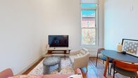 Located at 305 N Second St in Richmond, Virginia, this thoughtfully designed single-floor residence blends contemporary finishes with the character of a historic urban neighborhood. Warm hardwood floors run throughout, complementing the clean white walls and abundant natural light that streams through tall double-hung windows offering charming views of the surrounding brick architecture.

The kitchen is a standout feature, boasting crisp white shaker cabinetry with matte black hardware, white quartz countertops, a full suite of stainless steel appliances, and a central island that provides additional prep and gathering space. Elevated ceilings in the kitchen add an airy, open feel.

The living area is bright and inviting, with generous wall space and a large window framing tree and streetscape views, creating a welcoming atmosphere for relaxing or entertaining.

The bedroom is comfortably appointed, featuring a dedicated closet for ample storage, hardwood flooring, and a sizable window that fills the room with natural light and views of the neighborhood's historic buildings.

The bathroom showcases a sleek, modern aesthetic with large-format marble-look wall tiles, a glass-enclosed walk-in shower with decorative mosaic floor tile, white cabinetry, and clean, contemporary fixtures. This residence offers a refined urban living experience in the heart of Richmond.