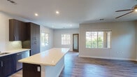 Located at 2760 Lake Pointe Dr in Spring Valley, CA, this single-story home offers a thoughtfully designed layout with contemporary finishes throughout. The open-concept kitchen is a standout feature, equipped with dark espresso cabinetry, stainless steel appliances including a refrigerator, gas range, microwave, and dishwasher, complemented by crisp white quartz countertops and a central island that flows seamlessly into the living and dining areas. Recessed lighting illuminates the space, while large windows invite abundant natural light and provide views of the surrounding greenery. Wood-look flooring extends throughout the main living areas, adding warmth and continuity to the design. The bedrooms are well-proportioned, each featuring ceiling fans, neutral-toned walls, and windows that frame outdoor views. The bathrooms are finished with clean, modern fixtures — one featuring a full soaking tub with subway tile surround, and another with a double-sink vanity and a glass-enclosed walk-in shower. The overall ambiance of the home is bright, clean, and move-in ready, combining functional design with modern aesthetic details that create a comfortable and inviting living environment.