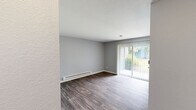 Located on the ground floor in Lakewood, WA, this well-appointed one-bedroom, one-bathroom unit offers a comfortable and functional layout. The living area features durable hardwood-style flooring, neutral gray walls, and a baseboard heating system. A sliding glass door with vertical blinds fills the space with natural light and opens to a pleasant outdoor view, creating an inviting atmosphere.

The kitchen is thoughtfully updated with gray shaker-style cabinetry, crisp white countertops, and black appliances including an electric range and refrigerator. A large window above the counter brings in additional natural light, and ample cabinet space provides generous storage. The kitchen flows efficiently into the rest of the unit.

The bedroom is a comfortable, well-proportioned room with soft carpeting, a window with blinds, a baseboard heater, and a sliding-door closet offering practical built-in storage. The bathroom includes a full tub-shower combination with a curved curtain rod, a toilet, and a vanity, finished with clean, neutral tones.

Throughout the unit, the consistent color palette of soft grays and whites creates a cohesive, modern feel. The textured ceilings and clean white trim add subtle architectural detail, making this a practical and attractive space in the Lakewood community.