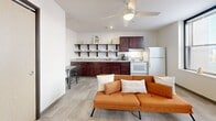 Located at 1004 N 10th St in Milwaukee, WI, this one-bedroom, one-bathroom unit offers a well-designed layout that maximizes every inch of its compact footprint. The open-concept living and kitchen area serves as the heart of the space, where a ceiling fan overhead and multiple windows allow natural light to fill the room, creating a bright and airy atmosphere. Light-toned tile flooring runs throughout, lending consistency and a clean aesthetic across all areas.

The kitchen is thoughtfully appointed with rich dark wood cabinetry, granite-look countertops, a double-basin sink, and white appliances including a range and refrigerator. Open shelving above the counters adds both storage and visual interest, while a small dining area nearby provides a convenient spot for everyday meals.

The living area offers comfortable room for seating and relaxation, with a view that connects seamlessly to the kitchen, making the space feel larger than its footprint suggests.

The bedroom is a cozy, private retreat with clean white walls and tile flooring, providing a quiet space to unwind. The bathroom features a dark wood vanity with a white countertop, a large mirror, and a walk-in shower enclosed by a glass door, completing the unit with a polished, modern finish.