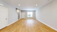 This two-story residence in Farmington, CT offers a thoughtfully designed layout across two floors, providing comfortable living with two bedrooms and two full bathrooms. The main level features an open-concept kitchen and living area finished with warm light wood flooring and neutral gray walls throughout. The kitchen is a standout, showcasing white shaker-style cabinetry, granite countertops, a subway tile backsplash, a central island with pendant lighting, and a full suite of stainless steel appliances. A sliding glass door brings in abundant natural light and connects the kitchen to the exterior. The spacious living room offers recessed lighting and a welcoming entry with a staircase leading to the upper level. Upstairs, the primary bedroom is generously sized and includes a well-organized walk-in closet with wire shelving. The second bedroom is bright and airy, with a window and recessed lighting. Both bathrooms are cleanly finished with tile flooring, dark-toned vanities, white countertops, and brushed nickel fixtures — one featuring a tub/shower combination. The home's consistent use of light hardwood flooring, soft neutral tones, and modern fixtures creates a cohesive, contemporary ambiance throughout.