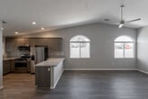 This single-story home on Olive Street in Hesperia, California presents a well-designed layout with contemporary finishes throughout. The open-concept living and dining area is anchored by vaulted ceilings that lend an airy, expansive feel, complemented by wood-look plank flooring and neutral toned walls. A ceiling fan overhead and an arched window allow natural light to fill the space generously.

The kitchen is appointed with dark-stained cabinetry, granite countertops, and a full suite of stainless steel appliances, including a gas range, built-in microwave, refrigerator, and dishwasher. A peninsula counter connects the kitchen to the living area, making it well-suited for both everyday use and entertaining.

The bedrooms feature plush carpet flooring, vaulted ceilings, ceiling fans, and sliding glass door access to the exterior. Walk-in closets with built-in shelving and hanging rods provide organized storage. Both bathrooms include granite-topped vanities with dark wood cabinetry and hardwood-style flooring, with one bathroom offering a shower-tub combination.

The attached garage features a concrete floor and an automatic opener, offering ample storage and parking capacity.