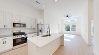 This contemporary 1020 square foot residence in Wilmington, NC offers a harmonious blend of style and functionality. The single-story layout encompasses two bedrooms and two bathrooms, with the primary bedroom boasting a generous 170 square feet. The heart of the home is an open-concept kitchen and living area, characterized by high ceilings that create a sense of spaciousness and large windows that flood the interior with natural light.

The gourmet kitchen is a standout feature, showcasing sleek white cabinetry, a subway tile backsplash, and modern stainless steel appliances. A central island with a built-in sink provides additional workspace and casual dining options. The living area seamlessly connects to the kitchen, offering a perfect space for entertaining or relaxation.

Both bathrooms are thoughtfully designed with modern fixtures and ample storage. The home includes two closets for added convenience, and a dedicated laundry room with full-sized appliances enhances the property's practicality. Throughout the residence, light wood flooring adds warmth and complements the crisp white walls, creating a fresh and inviting atmosphere.

Large windows in the living area and bedrooms not only brighten the space but also offer pleasant views of the surrounding landscape. The property's design emphasizes a seamless indoor-outdoor connection, with a door leading to an exterior space, perfect for enjoying the North Carolina climate.